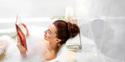 Une femme lit dans un bain à bulles avec des bougies allumées