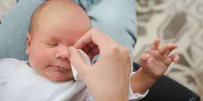 Des parents nettoient les yeux d'un bébé