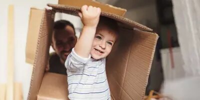 Un petit garçon tient une boîte en carton pendant un déménagement avec sa famille